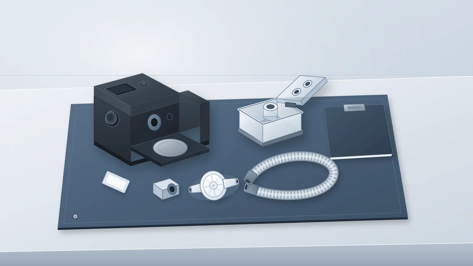 Illustrated still life of an unbranded CPAP flow generator with its humidifier bay empty, beside an open cleanable humidifier tub, a removed outlet connector, an inlet filter, an in-line bacterial filter, coiled air tubing and a closed maintenance binder on a slate-blue workbench mat.